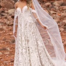 Különleges hímzett csipkével díszített A vonalú menyasszonyi ruha mély - tüllbetéttel kombinált -szív alakú kivágással. Érdekessége a bő, levehető csipkeujj, mely bohém külsőt kölcsönöz a modellnek. Egy igazán rendkívüli darab az Evie Young esküvői ruha kollekcióból! Style: Wyatt. Fátyollal
